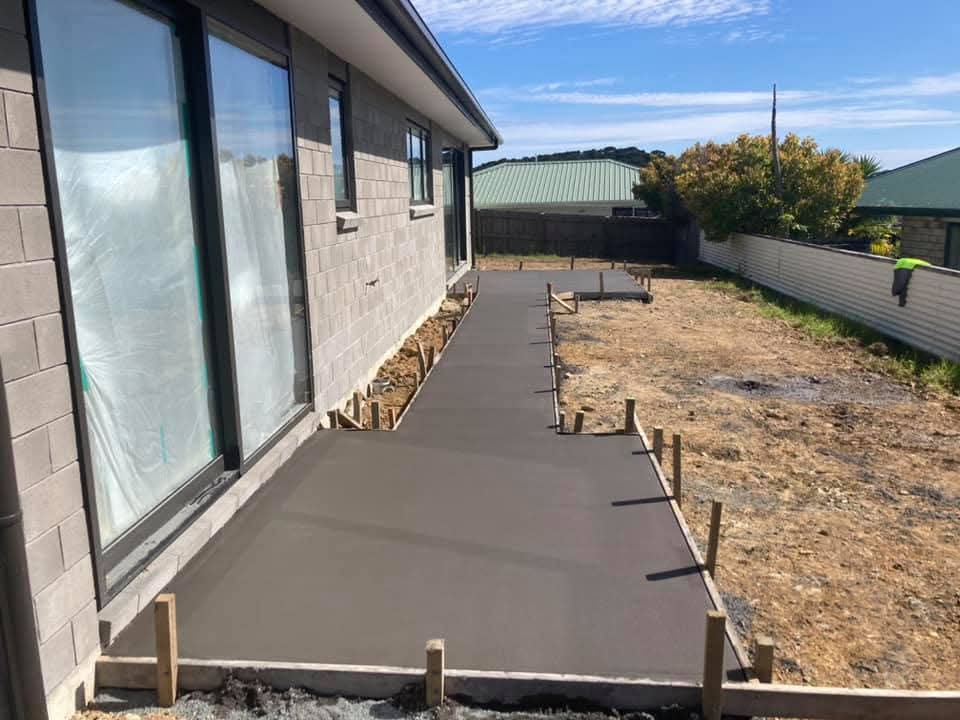 Long finished concrete footpath running alongside a new home in bright sunlight, by Henwood Concrete