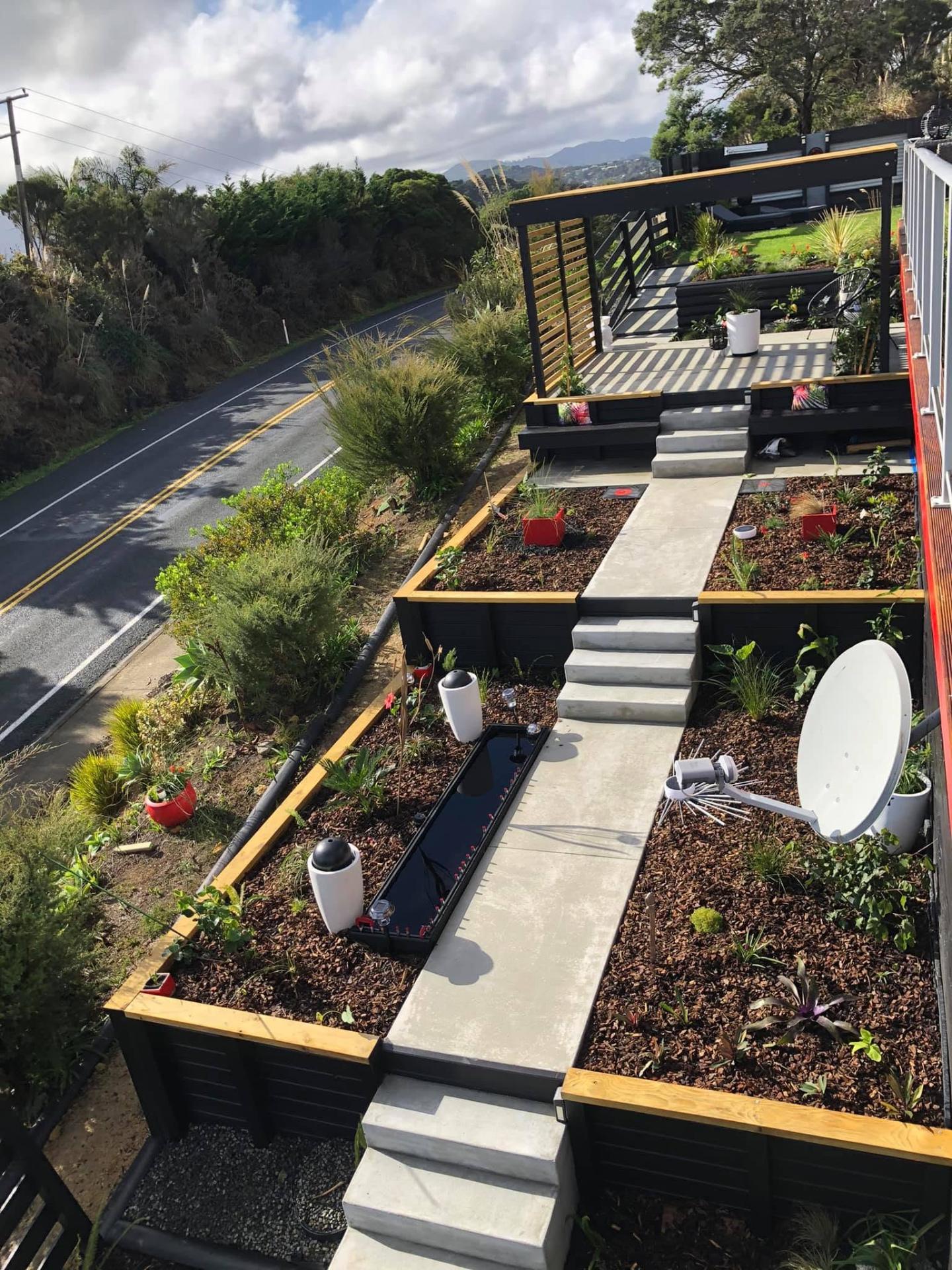 Long concrete pathway and steps through landscaped garden beds beside a road, by Henwood Concrete
