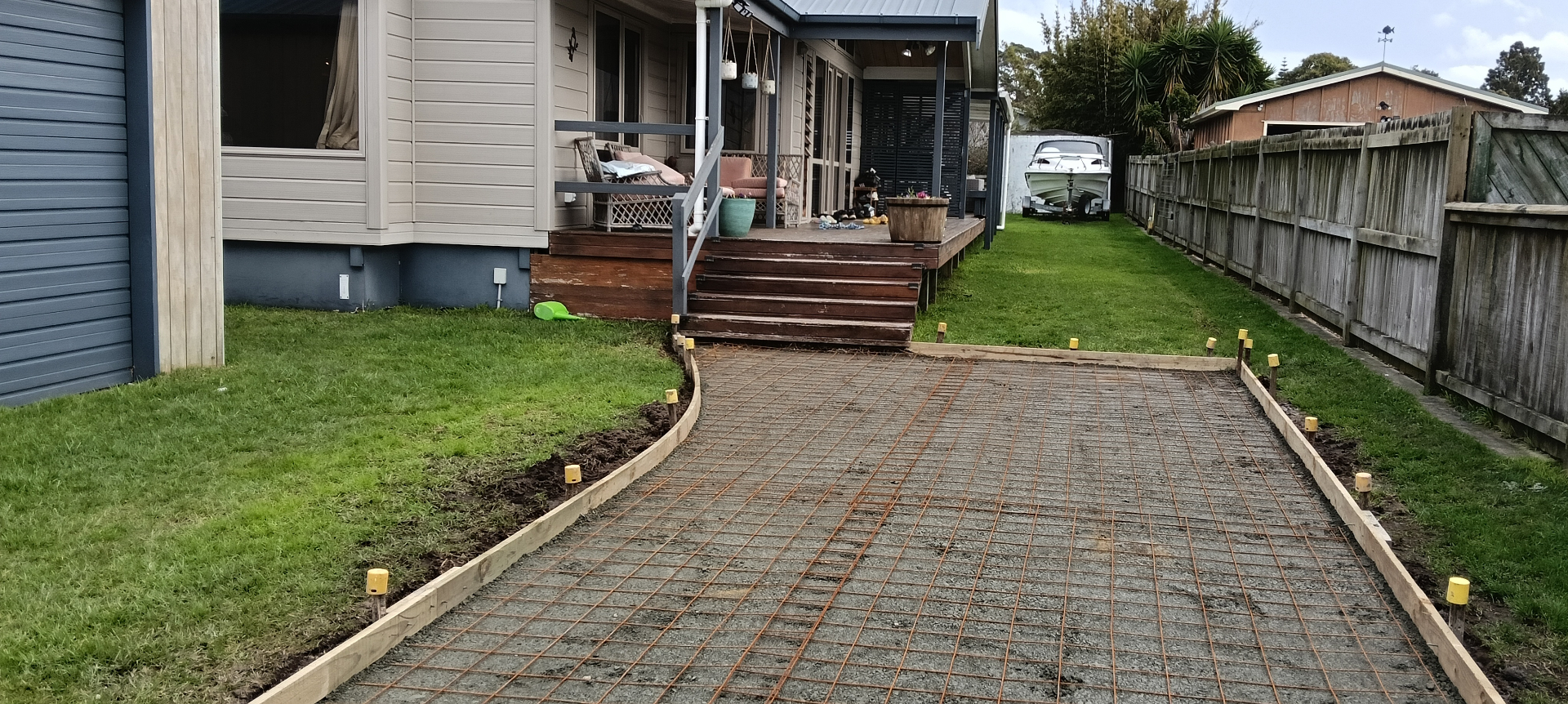 Curved concrete driveway area with timber boxing formwork and steel reinforcing mesh leading toward a house, by Henwood Concrete