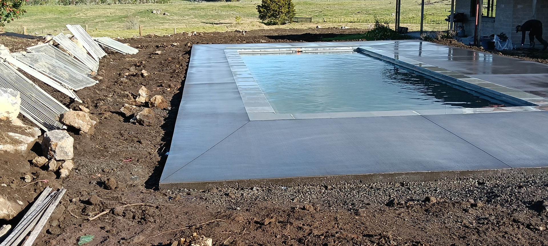 Finished concrete pool surround with the swimming pool centred and the surrounding concrete deck clearly visible, by Henwood Concrete.